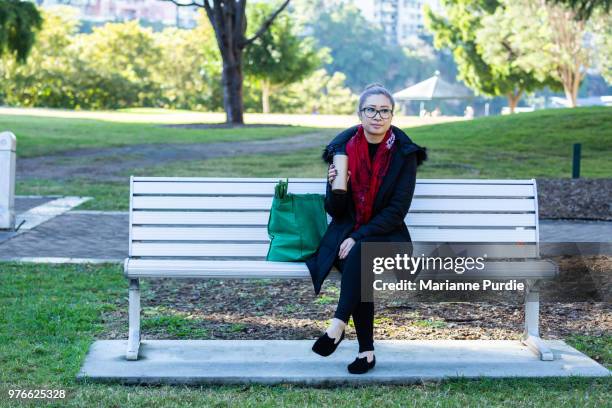 a lady with a travel mug and reusable grocery bag sitting on a park bench - buste marianne foto e immagini stock