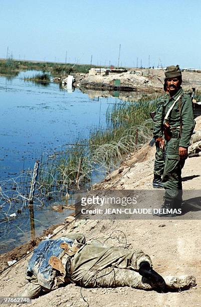 An Iraqi soldier stands near the corpses of Iranian soldiers laying in the swamp near the Iraqi city of al-Howeizah, north of Basra, on March 20,...