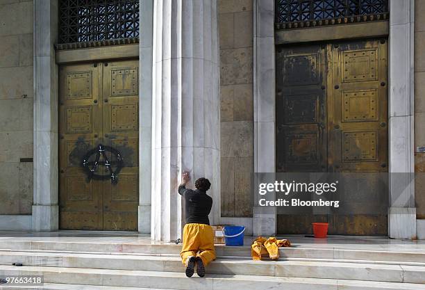 Worker removes graffiti from the central bank of Greece in Athens, Greece, on Friday, March 12, 2010. European Union finance ministers will discuss...