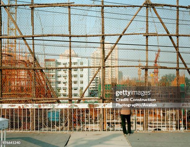 Woman looking down at construction site, Beijing, China.