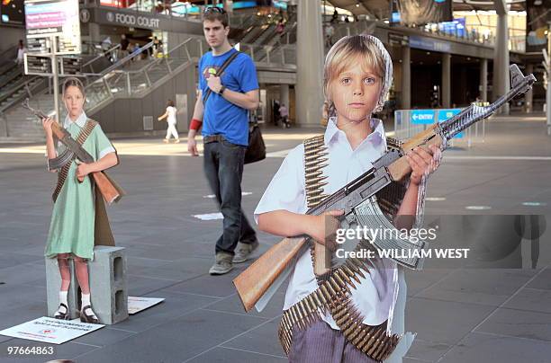 Man inspects cardboard cut-outs of children armed with weapons at Melbourne's Southern Cross train station, which is part of a national campaign by...