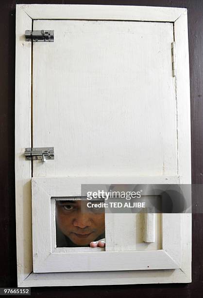 Military personnel peers from a small window of the former detention cell of the late president Corazon Aquino's husband Benigno "Ninoy" Aquino...