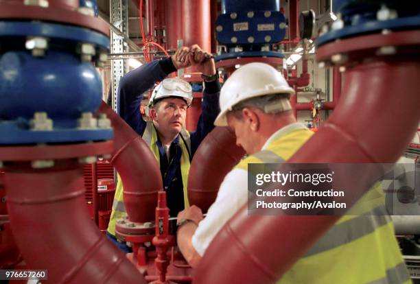 Two workers working as a team, Tightening valves using a spanner.