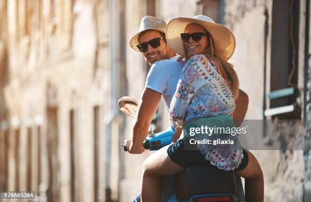 couple on a scooter bike driving through city streets. - couple scooter stock pictures, royalty-free photos & images