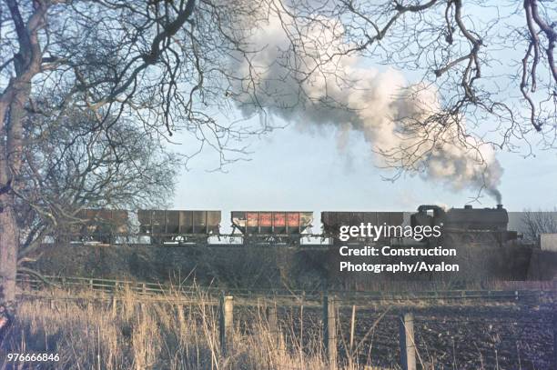 The familiar silhouette of a Hunslet Austerity caught with a rake of loaded wagons at Shilbottle Colliery, Northumberland. January 1973.