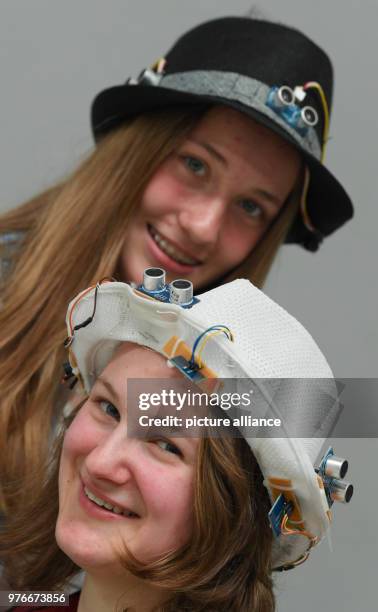 April 2018, Germany, Darmstadt: Anna-Maria Koetter and Franziska Benzin of the 'Ziehenschule Frankfurt' presen ttheir hats at the competition 'Jugend...