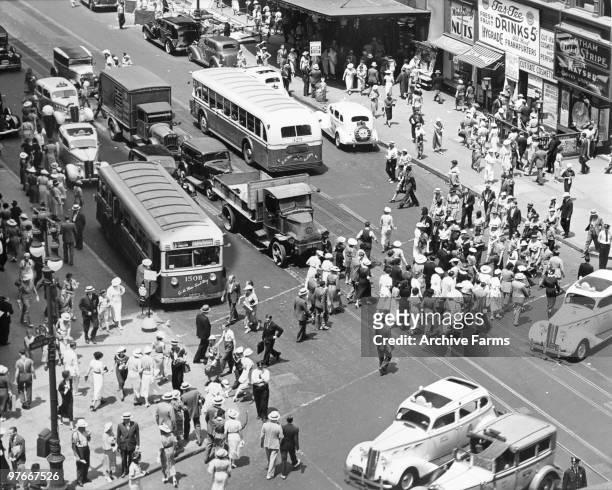 View looking down onto the pedestrian and vehicular traffic on the busy intersection of 34th Street and Broadway, off Herald Square, 1936. People can...