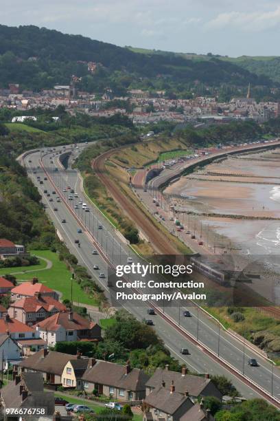 First North Western Class 175 with a service from Holyhead runs alongside the A55 trunk road as it skirts the North Wales coast at Colwyn Bay. July...