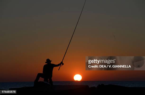 Fisherman at sunset on the dock of Vernazza , Cinque Terre National Park, Liguria, Italy.
