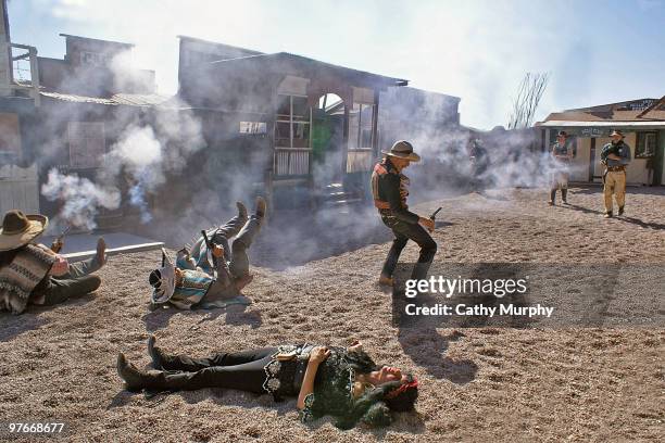 Through a thick layer of gunsmoke, Tombstone marshals blow away 'Mexican' banditos, as actors sprawl across the ground during a western scene...