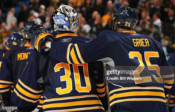 Ryan Miller of the Buffalo Sabres skates off the ice with teammate Michael Grier following their overtime victory over the Philadelphia Flyers on...