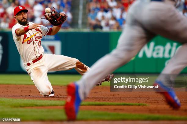 Matt Carpenter of the St. Louis Cardinals attempts to throw to first base against the Chicago Cubs in the second inning at Busch Stadium on June 16,...