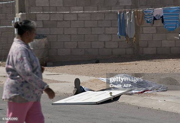 Woman walks past the covered corpse of a man killed by drug traffickers in front to his home in Ciudad Juarez, Mexico, on March 12, 2010. Ciudad...