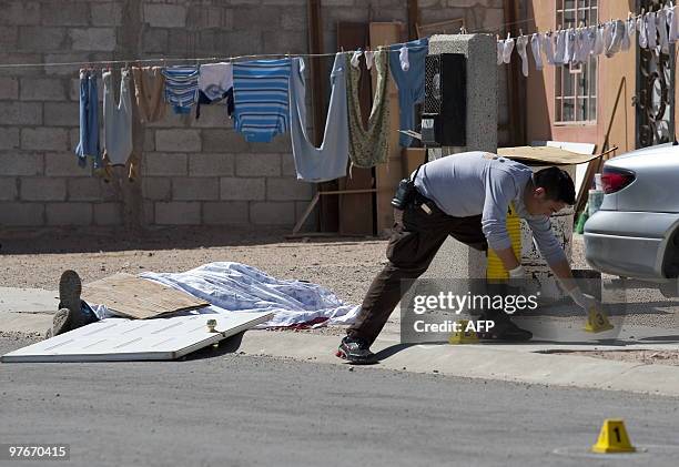 Police officer places markers next to the corpse of a man killed by drug traffickers in front to his home in Ciudad Juarez, Mexico, on March 12,...