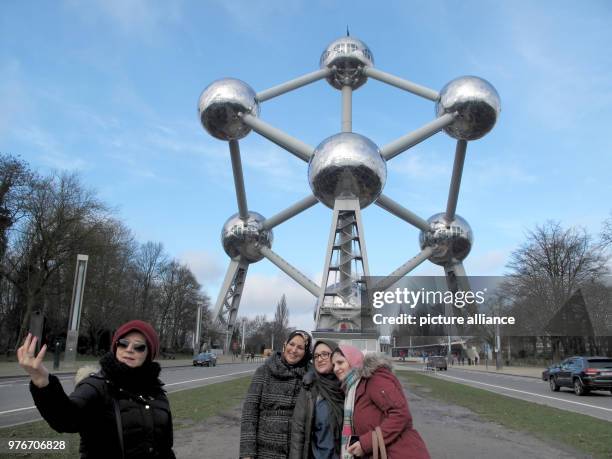 January 2018, Belgium, Brussels: Tourists take selfies in front of the 102m tall Atomium building. The Atomium was created for the World Exhibtion of...