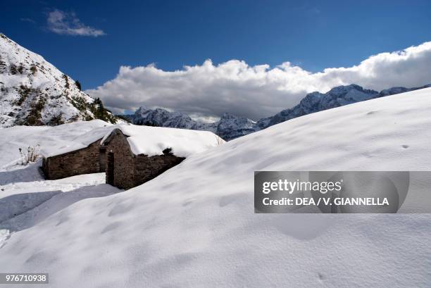 Snow-covered cabins in the upper Val Canale with the Pizzo Arera in the background, Orobian Pre-Alps, Park of the Bergamo Orobian Mountains,...