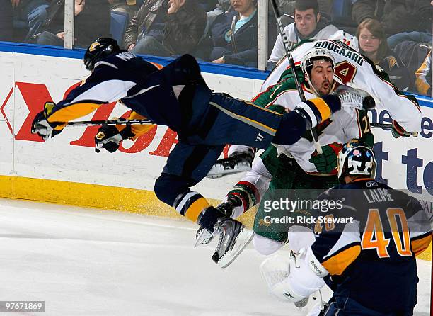 Steve Montador of the Buffalo Sabres gets airborne and strikes Cal Clutterbuck of the Minnesota Wild with his skate as Patrick Lalime of the Sabers...