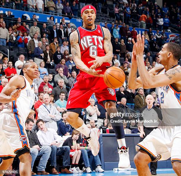 Courtney Lee of the New Jersey Nets passes the ball in mid-air around through the defense of Thabo Sefolosha and Russell Westbrook of the Oklahoma...