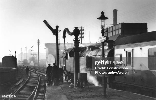 Mansfield Town at Christmastide. In arctic cold the water column is frozen despite the brazier as Stanier 2-6-2T No 40175 stands at the head of a...