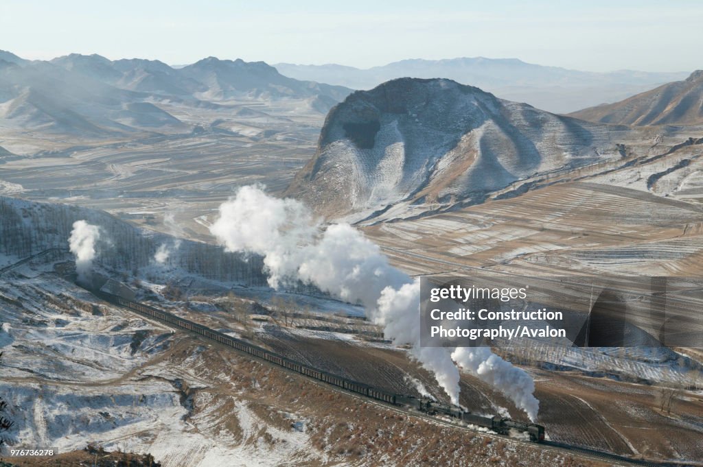 The bleak winter landscape of the Jing Peng pass provides a fine backdrop to a double-headed coal train emerging from tunnel No 4 and leaving wraiths of steam oozing from the tunnel mouth. This mountainous section of the Ji-Tong railway across Inner Mong