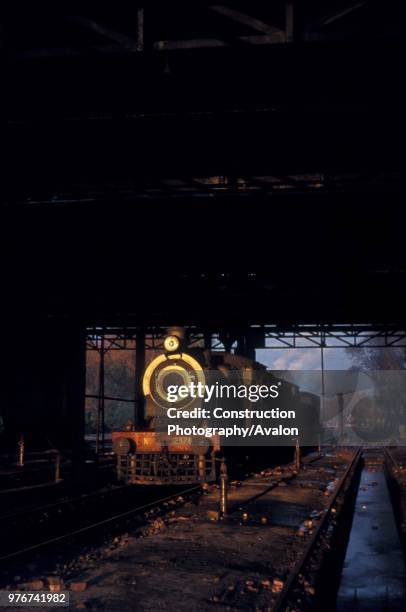 The late afternoon sun shines through the motive power depot at Malakwal in the Pakistan Punjab and illuminates an SPS class inside cylinder 4-4-0 of...