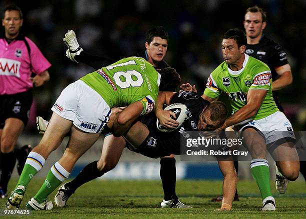 Luke Lewis of the Panthers is tackled by the Raiders during the round one NRL match between the Penrith Panthers and the Canberra Raiders at CUA...