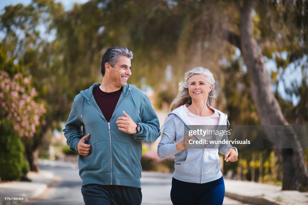 Happy multi-ethnic retired mature couple jogging together in spring