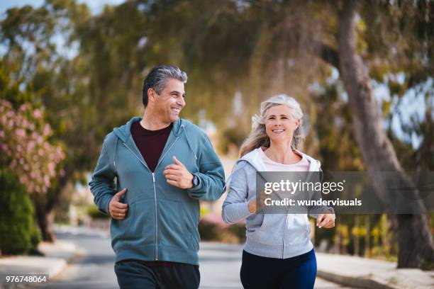 happy multi-ethnic retired mature couple jogging together in spring - couple senior sport stock pictures, royalty-free photos & images