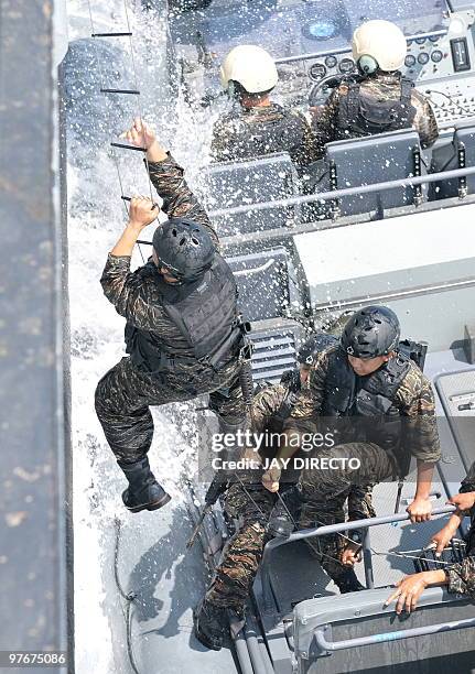 Members of the Philippines Navy climb up to board a ship during a joint military exercise with US navy personnel in Manila Bay on March 13, 2010. The...