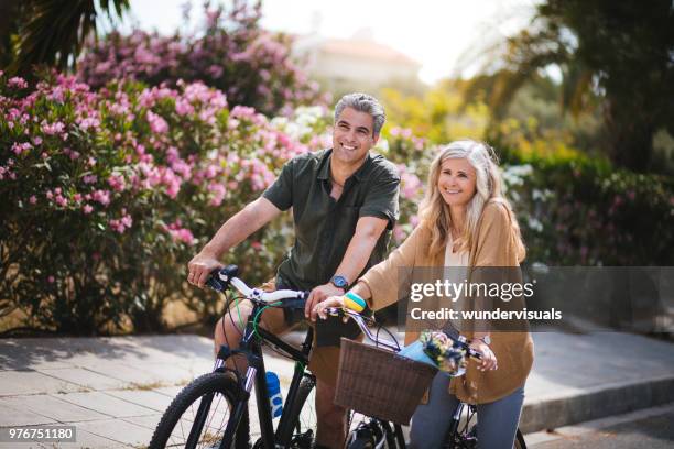 smiling active senior man and woman riding bicycles in spring - bike flowers stock pictures, royalty-free photos & images