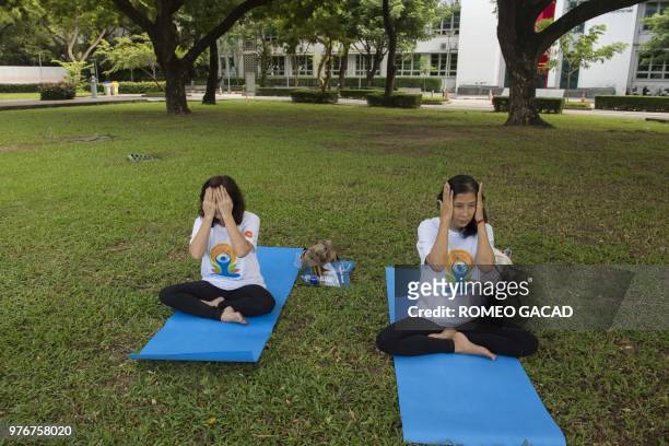 Two Thai women participate in a mass yoga session attended by hundreds of people at the grounds of Chulalongkorn University in Bangkok on June 17...