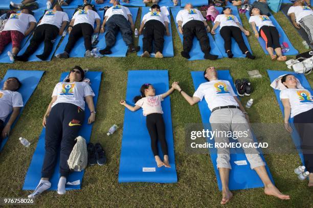 Man and a child hold hands as they participate in a mass yoga session at the grounds of Chulalongkorn University in Bangkok on June 17 ahead of the...