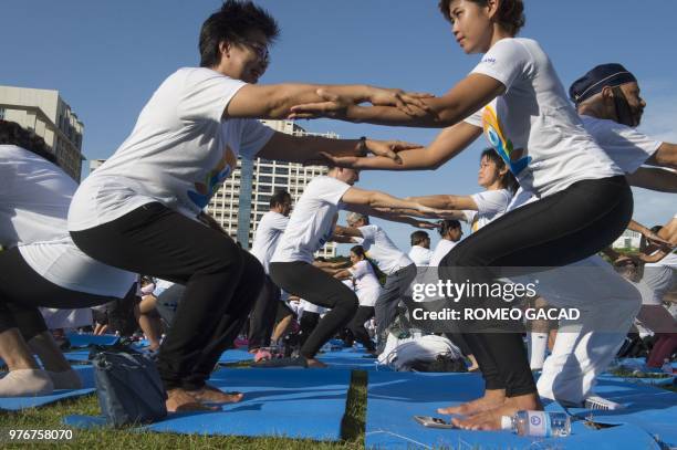 Participants hold hands during a mass yoga session attended by hundreds of people at the grounds of Chulalongkorn University in Bangkok on June 17...