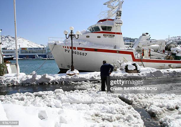 Man shovels snow on a dock of the harbour of the French southern city of Port-Vendres after heavy snowfall on the Pyrenees region on March 9, 2010. A...