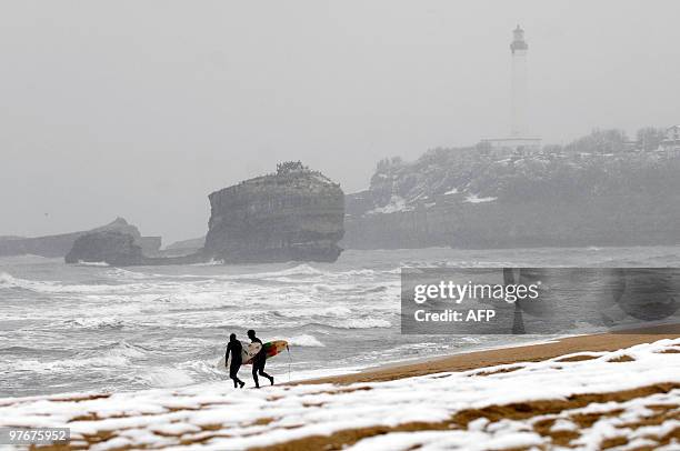 Surfers walk on a snow covered beach in the French southern city of Biarritz after heavy snowfall on the Pyrenees region on March 10, 2010. A freak...