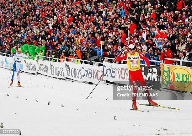 Norway's Petter Northug crosses the finish line to win the 50km men free technique race ahead of Italian Pietro Piller Cottrer in the Holmenkollen...