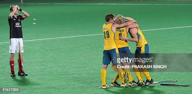German hockey player Florian Fuchs looks dejected as Australian hockey players celebrate after defeating Germany in the World Cup 2010 final match at...