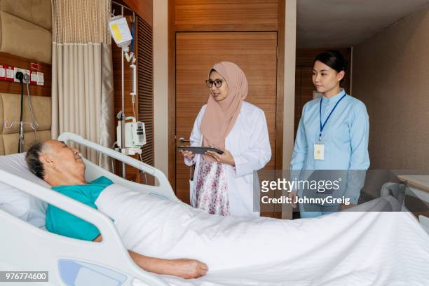 senior man in hospital bed talking to two medical staff - patient resting stock pictures, royalty-free photos & images
