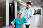 Senior man being pushed in wheelchair by male nurse