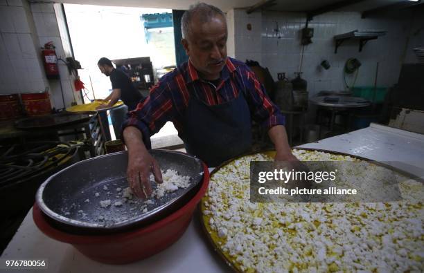 Dpatop - A Palestinian man prepares a tray of Kanafeh at Al-Aqsa sweets shop in the West Bank city of Nablus, 11 April 2018. Kanafeh, a traditional...