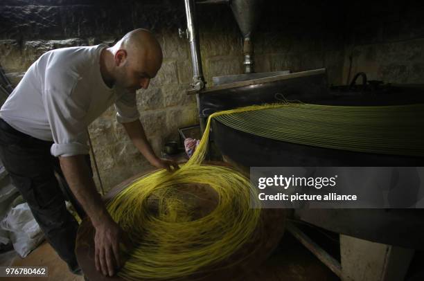 Palestinian man operates a machine making Kanafeh pastry at Al-Aqsa sweets shop in the West Bank city of Nablus, 11 April 2018. Kanafeh, a...