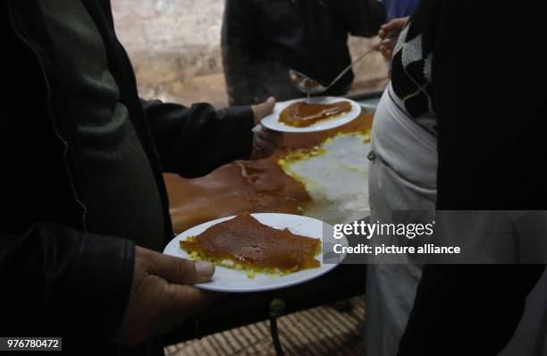Palestinian man hands plates of Kanafeh to a customer at Al-Aqsa sweets shop in the West Bank city of Nablus, 11 April 2018. Kanafeh, a traditional...