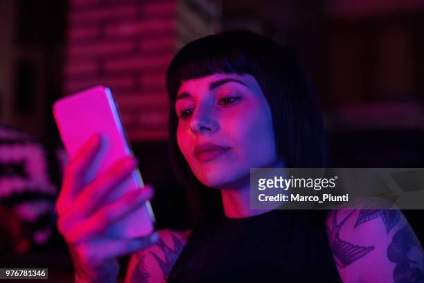 young woman typing phone message - neon lighting smiling stock pictures, royalty-free photos & images