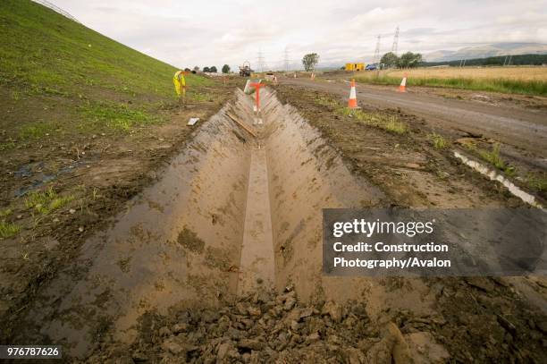 Drainage ditch dug out by a trapezoidal excavator bucket.