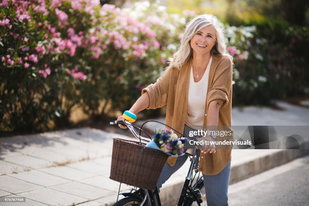 Mujer senior sonriente divertirse montar bicicleta vintage en primavera