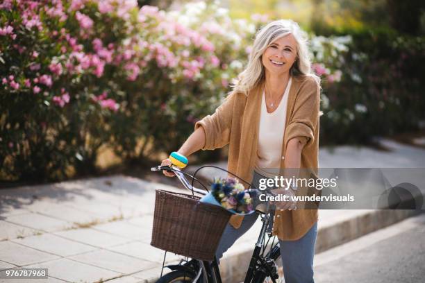 smiling senior woman having fun riding vintage bike in spring - só uma mulher idosa imagens e fotografias de stock