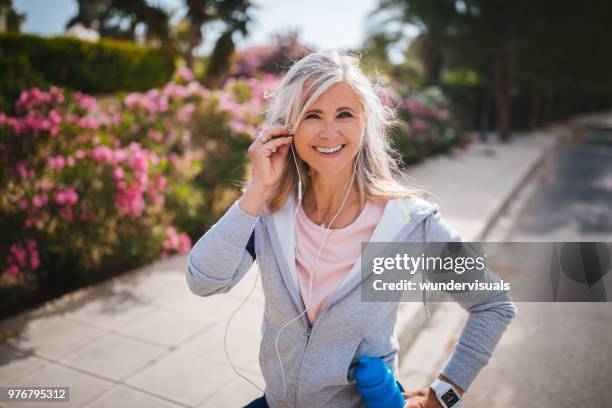 porträt von aktive reife frau anhören von musik vor dem joggen - old woman running stock-fotos und bilder