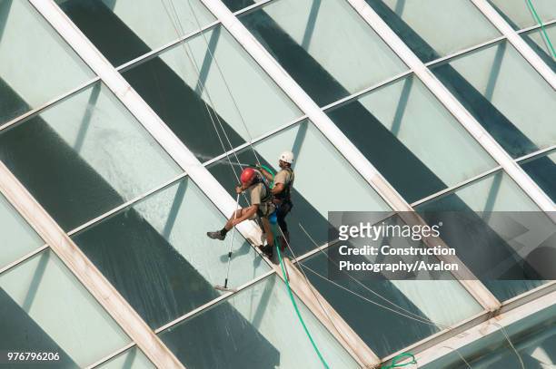 October 2009 - Valencia, Spain - Maintenance workers equipped with climbing gear are cleaning the glass facade of the Hemisferic. The Building is...