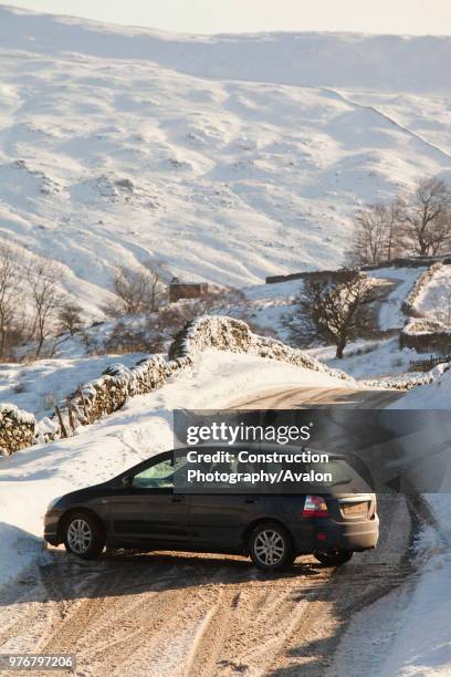 Car that skidded on ice on the Kirkstone Pass road above Windermere after it was blocked by spindrift and wind blown snow, Lake District, UK.