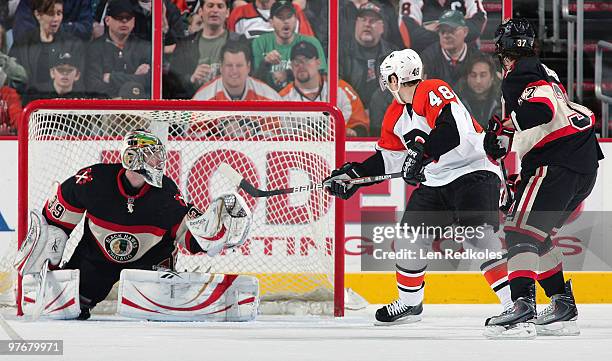 Danny Briere of the Philadelphia Flyers backhands the puck over the net against Cristobal Huet and Adam Burish of the Chicago Blackhawks on March 13,...